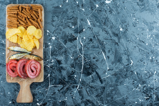 Varkensreuzel, vis, chips en paneermeel op een snijplank, op de blauwe tafel.