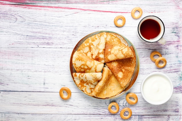 Vastenavond Maslenitsa festivalmaaltijd. Russische pannenkoekblini met frambozenjam, honing, verse room en rode kaviaar, suikerklontjes, kwark, bubliks op lichte achtergrond