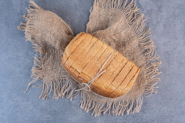 Vastgebonden blok gesneden brood op een stuk doek op marmeren achtergrond. hoge kwaliteit foto