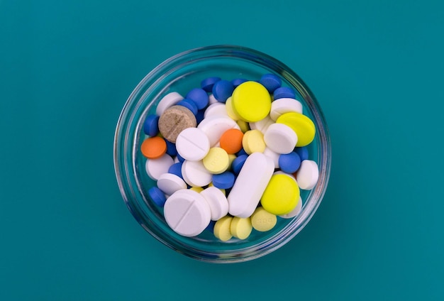 Veel farmaceutische pillen in een stellan kom op een blauwe achtergrond uitzicht van bovenaf Premium Foto