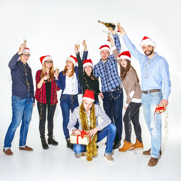 Veel jonge vrouwen en mannen drinken op kerstfeest op witte studio achtergrond
