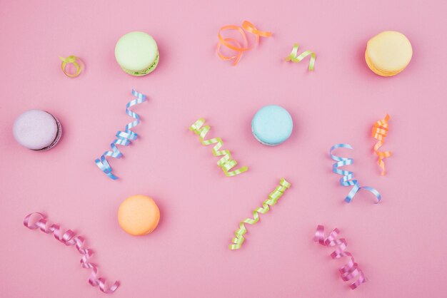 Veelkleurige bitterkoekjes met confetti op roze achtergrond