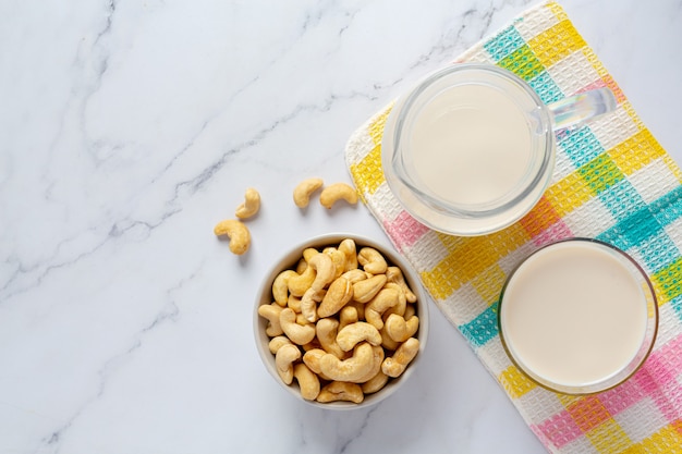 Veganistische cashewmelk in glas met cashewnoten op marmeren achtergrond