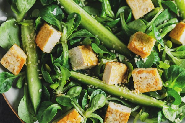 Veganistische salade met tofu, komkommer en sesam geserveerd op bord Close-up