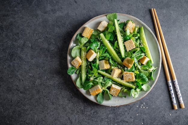 Veganistische salade met tofu, komkommer en sesam geserveerd op bord Close-up