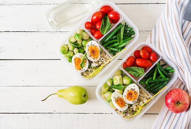 Vegetarische maaltijdbereidingscontainers met eieren, spruitjes, sperziebonen en tomaat. Diner in lunchbox. Bovenaanzicht. Plat liggen