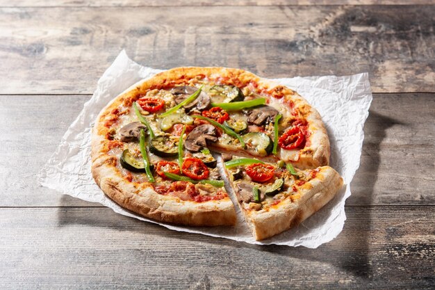 Vegetarische pizza met courgette, tomaat, paprika en champignons op houten tafel