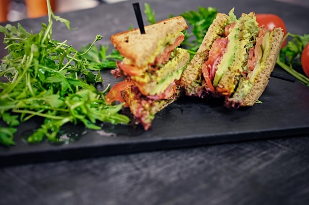 Vegetarische sandwich met salade en tomaten op een houten tafelblad.