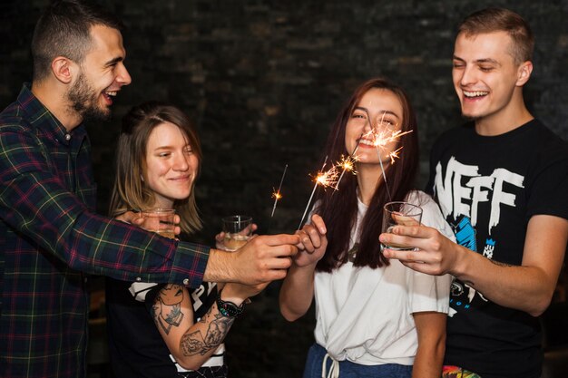 Vele gelukkige vrienden die dranken houden die fonkelen aansteken