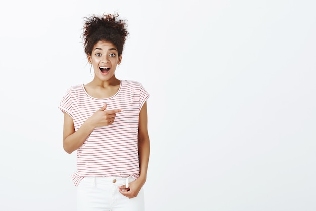 Verbaasd leuke vrouw met afro kapsel poseren in de studio