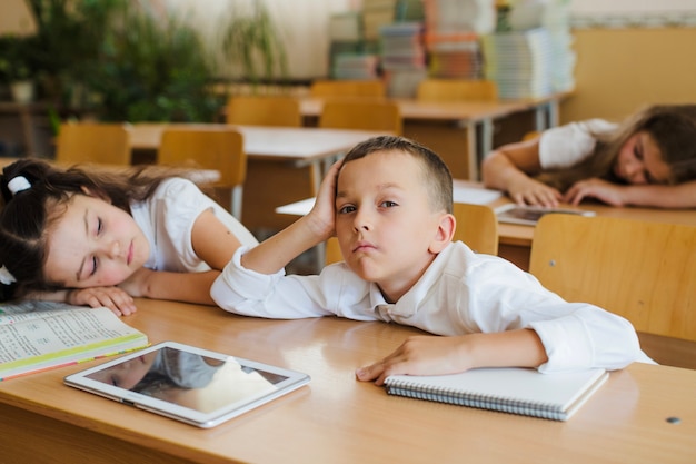 Verbaasde schooljongen aan tafel zitten