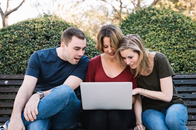 Verbaasde vrienden die laptop in park met behulp van