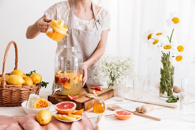 Verbazingwekkende geconcentreerde vrouw die citrusdrank kookt.