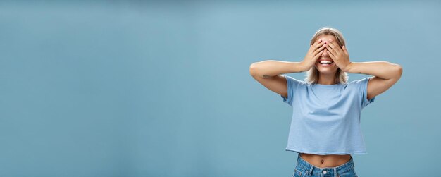 Gratis foto verberg je als je kan portret van zorgeloze en gelukkige knappe speelse meisje met blond haar glimlachend