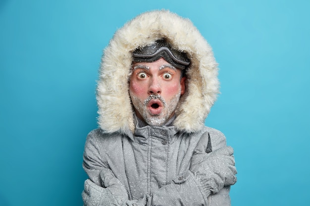 Gratis foto verbijsterde bevroren man met rood gezicht trilt van de kou omhelst zichzelf om warme blikken te voelen, afgeluisterde ogen draagt een snowboardbril.