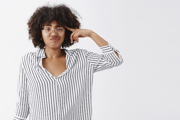 verdreven geïrriteerde knappe vrouw praat over vreemde en rare collega rollende vinger bij tempel grijnzend en fronsend van afkeer denken dat hij gek is