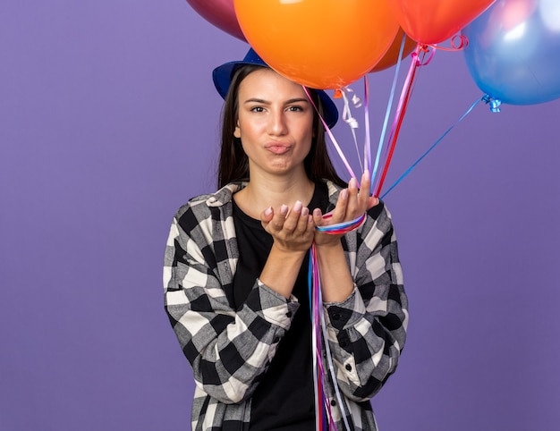 Verdrietig jong mooi meisje met feestmuts met ballonnen