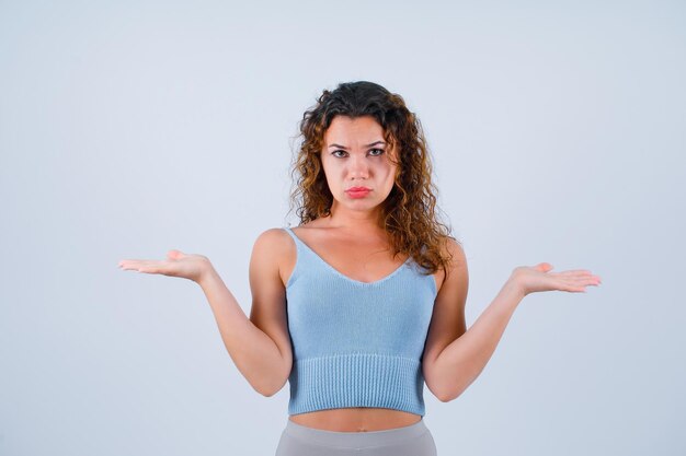 Verdrietig meisje kijkt naar de camera door haar handen wijd te openen op een witte achtergrond