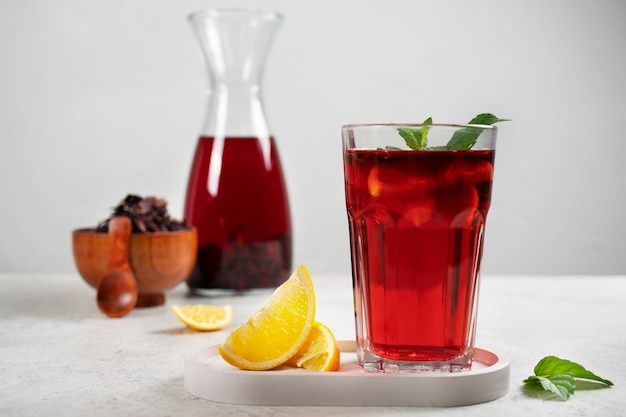 Verfrissende hibiscus-ijsthee in doorzichtige glazen container