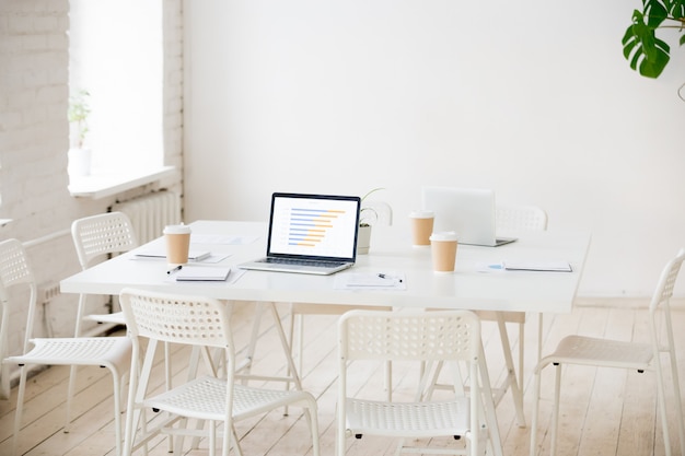 Vergadertafel met laptops en koffie in lege kantoorruimte