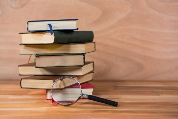 Vergrootglas met een stapel boeken op een tafel