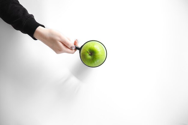 Vergrootglas met groene appel op witte achtergrond