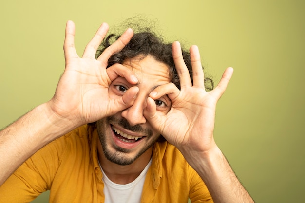 Vergrote weergave van de jonge knappe blanke man met bril geïsoleerd op olijfgroene muur