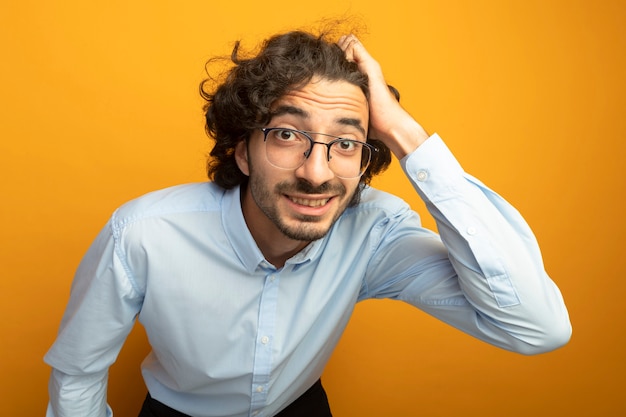 Gratis foto vergrote weergave van de jonge knappe man met bril kijken voorzijde geïsoleerd op oranje muur