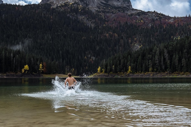 Gratis foto verharding in koud water man baadt in de herfst van het meer in montenegro durmitor park