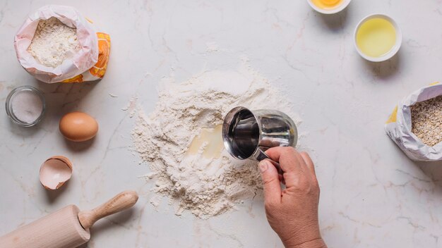 Verhoogde mening van het de hand gietende water van een bakker op bloem