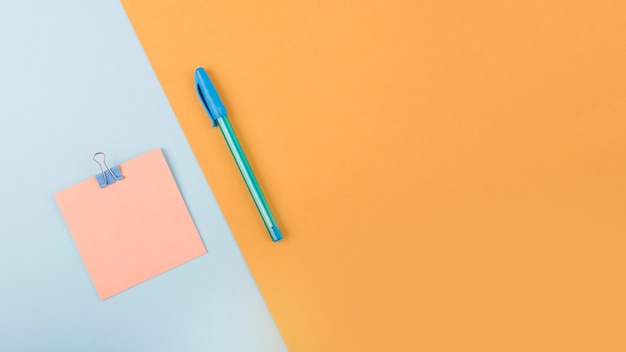 Verhoogde mening van zelfklevende nota en pen op kleurrijk kartonpapier