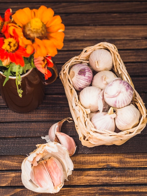 Verhoogde weergave van uien; knoflookteentjes en bloemen op houten oppervlak