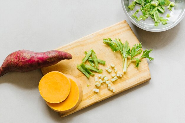 Verhoogde weergave van zoete aardappel; gesneden pompoen en selderij op snijplank