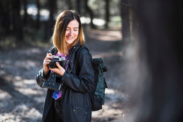 Verlegen vrouw met camera in bos