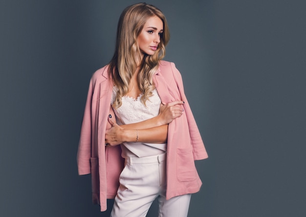 Verleidelijke blonde vrouw in roze jas poseren