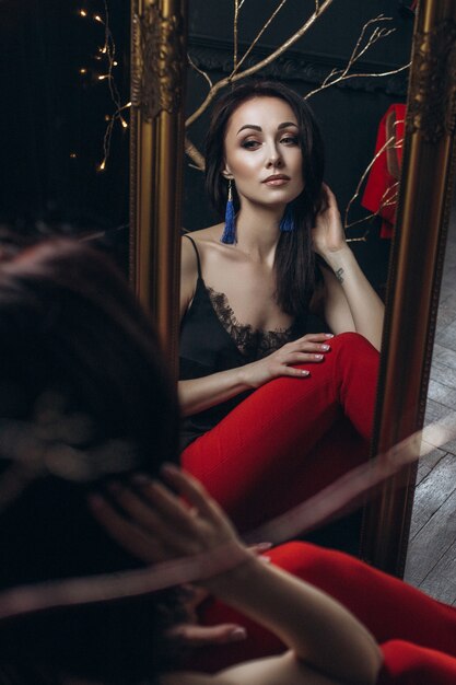 Verleidelijke vrouw in rood pak zit voor een spiegel