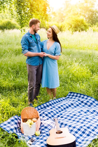 Verliefd paar knuffelen staande door geruite plaid op picknick