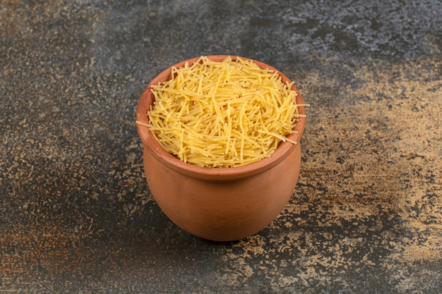 Vermicelli in een kom van klei, op de marmeren tafel.