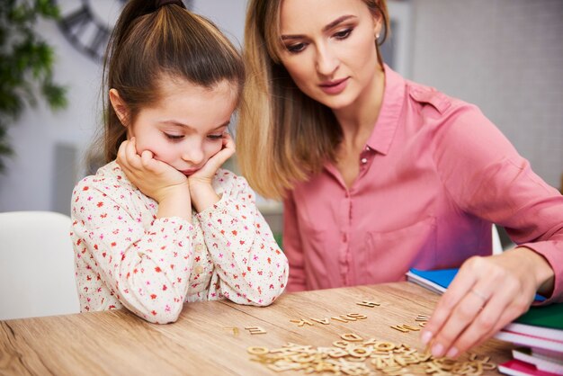 Vermoeid en verveeld kind en haar moeder die thuis aan het studeren is