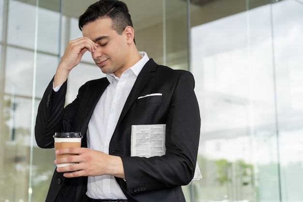 Vermoeide gefrustreerde zakenman die aan hoofdpijn lijdt