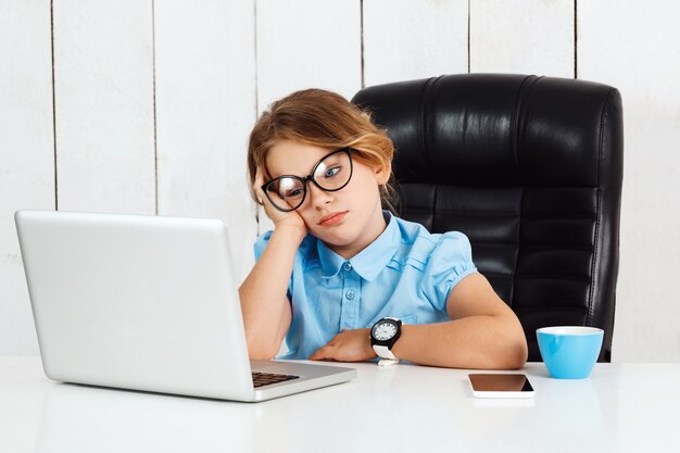 Vermoeide jonge mooie meisjeszitting op werkende plaats in bureau.