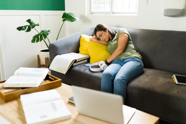 Vermoeide vrouw die in slaap valt terwijl ze probeert te studeren voor haar universiteitsexamens. Uitgeputte student die een dutje doet na het maken van huiswerk