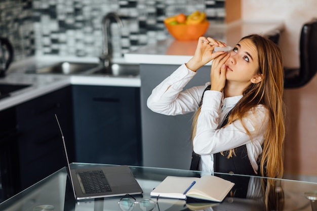 Vermoeide vrouw voelt vermoeide ogen na lang laptopgebruik thuis zitten