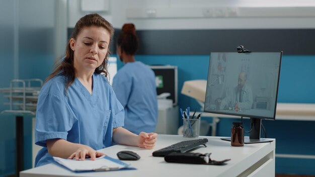 Verpleegkundige die videogesprek gebruikt voor gesprek met arts op computer. Medisch assistent in gesprek met dokter op online videoconferentie voor advies op afstand en telegeneeskunde terwijl hij in de kast zit