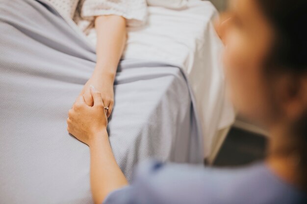 Verpleegkundige houdt de hand van haar patiënt vast