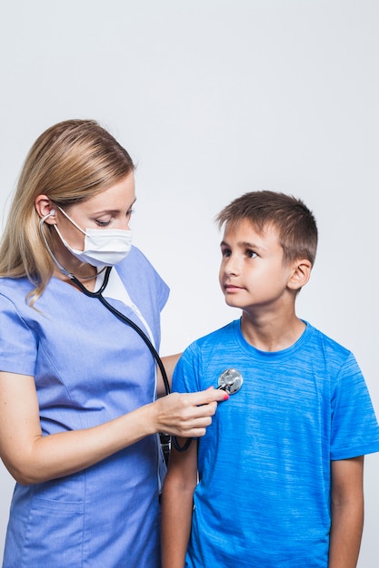 Verpleegster die jongen met stethoscoop onderzoekt