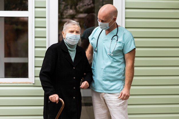 Verpleger poseren met oudere vrouw met stok