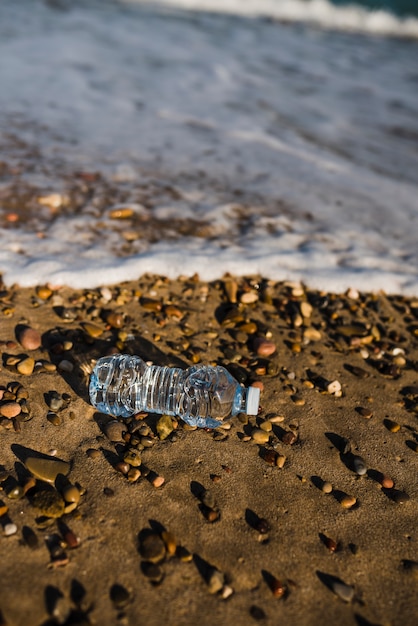 Gratis foto verpletterde plastic waterfles dichtbij de kust bij strand