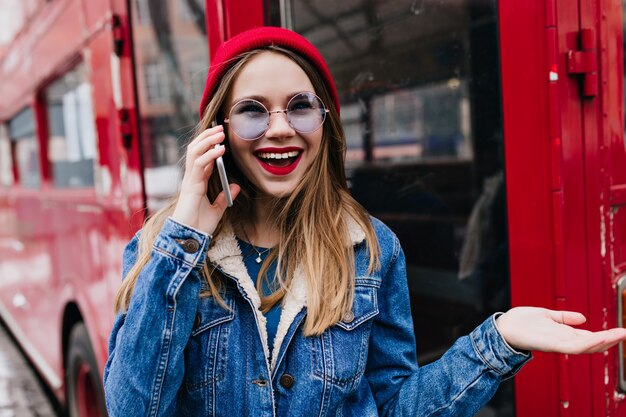 Verrast blanke vrouw in rode hoed praten over de telefoon.