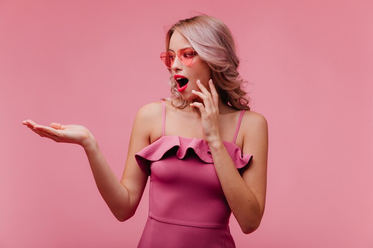 Gratis Foto verrast blonde vrouw die in zonnebril haar hand bekijkt